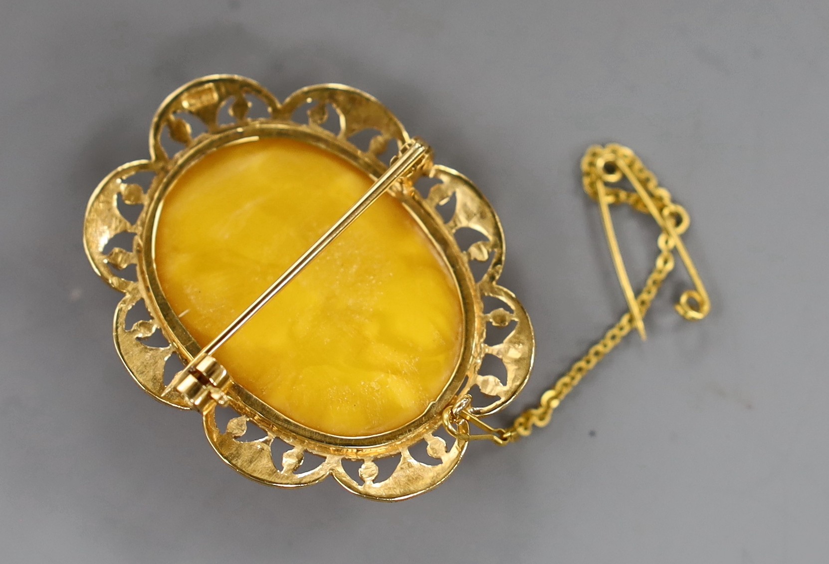 A 22ct mounted oval amber set brooch, 44mm, gross weight 12.1 grams.